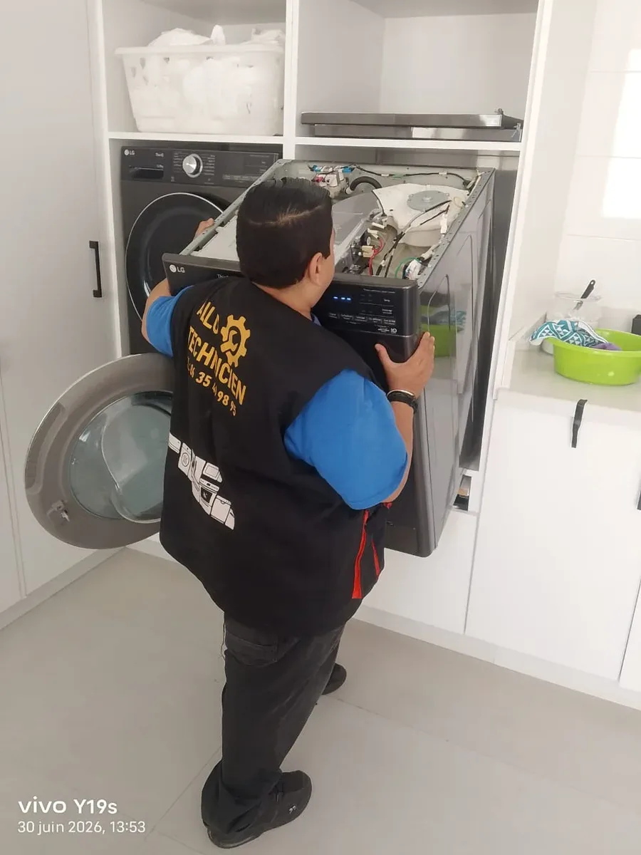 Technicien intervenant sur une machine à laver avec le hublot ouvert