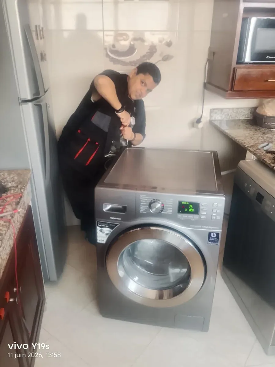 Technicien contrôlant un lave-linge dans une cuisine